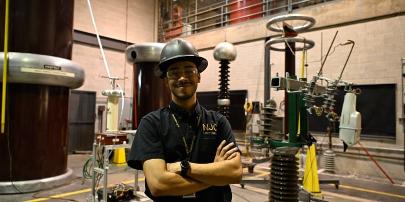 man smiling in a hard hat in a manufacturing room